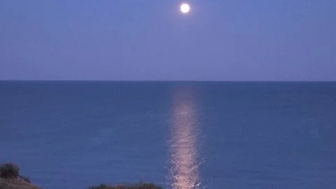 Bright full moon rising over the calm sea with a glowing light reflection on  Stock Footage 341475207