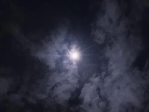 Bright full moon shining through dramatic dark clouds in the night sky Stock Photos