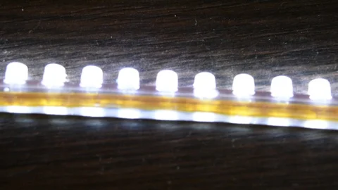 Bright glowing one LED strip DIP in silicone included and glowing on wooden Stock Footage 92868919