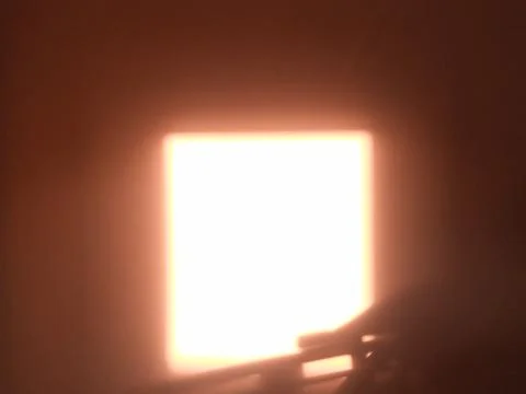 Bright glowing rectangular light in dark room with object silhouette 库存照片