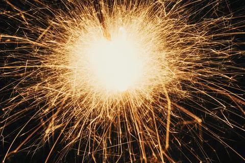 Bright glowing sparkler creating abstract golden light streaks in the dark .. Stock Photos