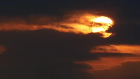 Bright glowing sun setting behind dramatic dark orange clouds, dramatic golden Stock Footage 346377716