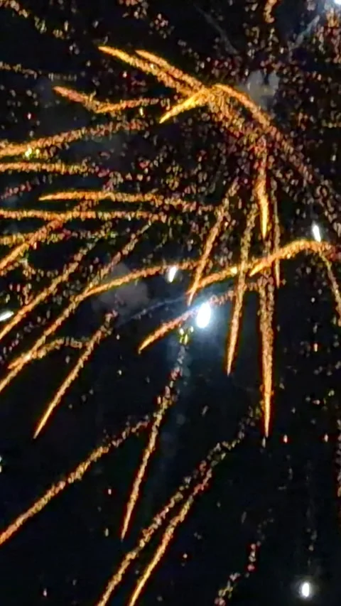 Bright golden fireworks exploding in a dark night sky, creating vibrant trails Video stock 345832165