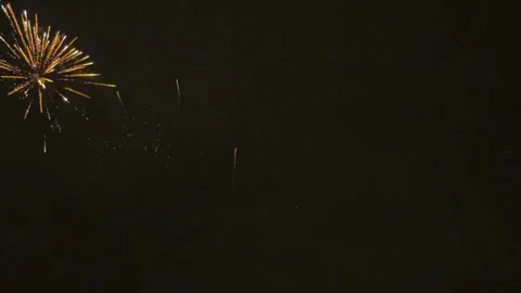 Bright golden fireworks exploding in the dark night sky, illustrating a festive Stock Footage 345973339
