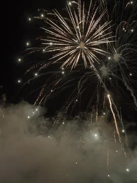 Bright golden fireworks exploding in dark night sky Stock Photos