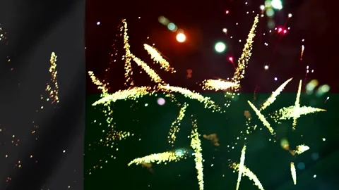 Bright golden fireworks exploding over a dark red and green wavy flag backg.. Stock-Footage 343690900