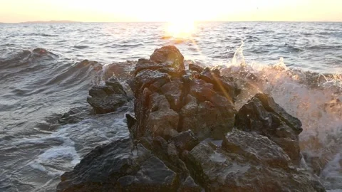 Bright golden sunset glowing over rugged coastal rocks and waves Stock Footage 337409446