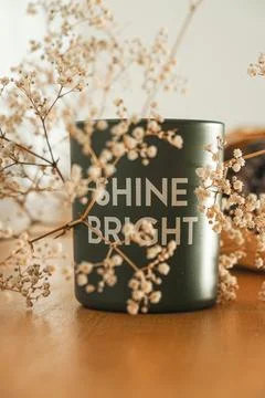 Bright green cup surrounded by delicate flowers adds warmth to the cozy scene 库存照片
