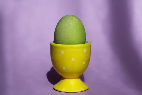 A bright green Easter egg in a special stand on a purple background. Easter d Photos