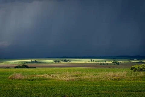Bright green fields glowing under a dark stormy sky, creating a dramatic na.. Stock Photos