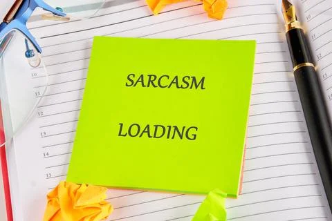A bright green note with Sarcasm Loading is displayed on a planner next to a Stock Photos