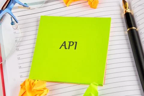 Bright green notepad featuring the term API is positioned among scattered cru Foto stock