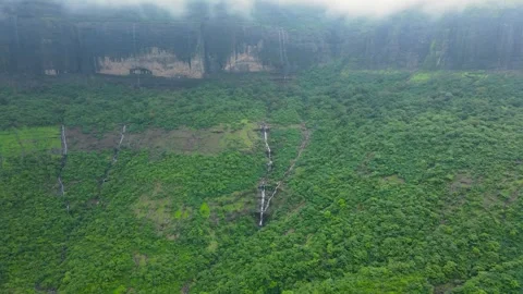 Bright green trees line cliffside as multiple waterfalls flow through the s.. Stock Footage 306120159