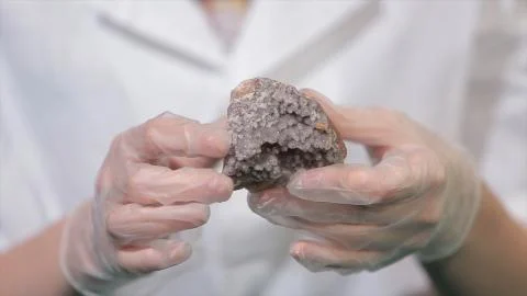 Bright grey ruby crystal ore in hands with gloves. Crystallization is the Stockfoto's