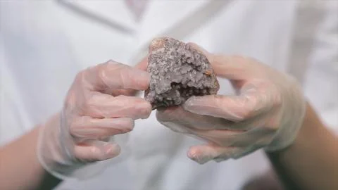 Bright grey ruby crystal ore in hands with gloves. Crystallization is the Stockfoto's