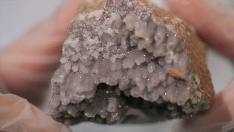 Bright grey ruby crystal ore in hands with gloves. Crystallization is the Stock Photos