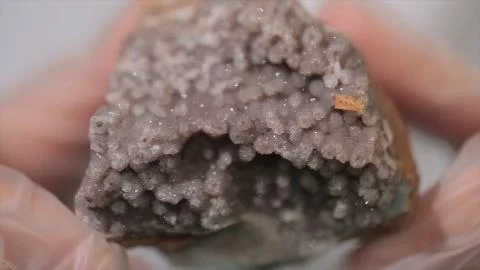 Bright grey ruby crystal ore in hands with gloves. Crystallization is the Stock Photos