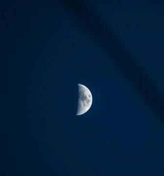 Bright half moon in sky during blue hour Stock Photos
