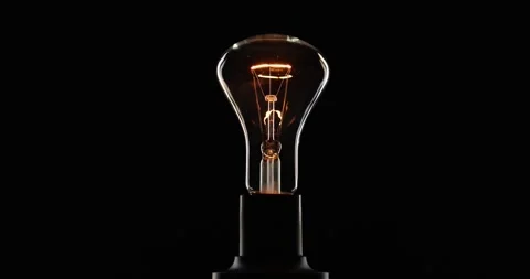Bright ignition and burning of an electric lamp on a black background Stock Footage 288450843