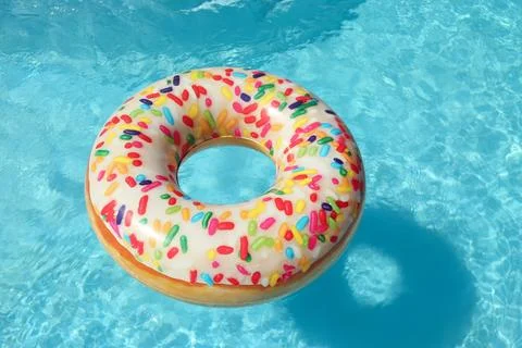Bright inflatable doughnut ring floating in swimming pool on sunny day Stock Photos