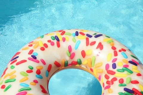 Bright inflatable doughnut ring floating in swimming pool on sunny day. Space 스톡 사진