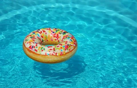 Bright inflatable doughnut ring floating in swimming pool on sunny day. Space Stock-Fotos