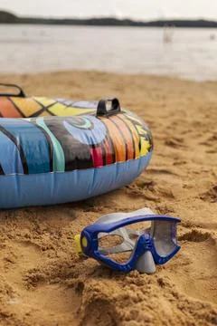Bright inflatable float with a vibrant design rests on warm sand, next to a.. Stock Photos