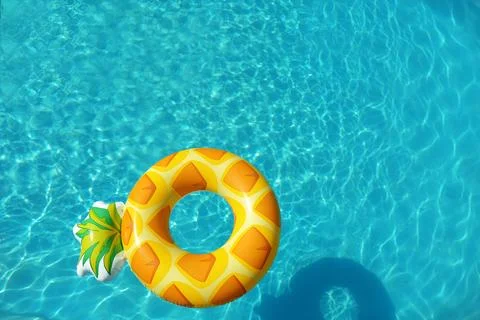 Bright inflatable pineapple ring floating in swimming pool on sunny day, abov 写真素材