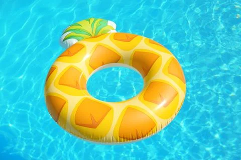 Bright inflatable pineapple ring floating in swimming pool on sunny day 스톡 사진