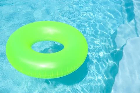 Bright inflatable ring floating in swimming pool on sunny day. Space for text Stock Photos