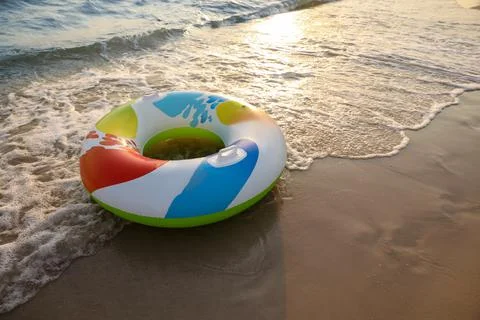 Bright inflatable ring on sunlit sandy beach near sea, space for text 스톡 사진