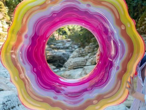 Bright inflatable swimming ring with multicolored striped pattern in nature Stockfoto's