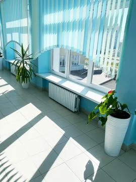 Bright interior space with large windows, featuring blue vertical blinds and Stock Photos
