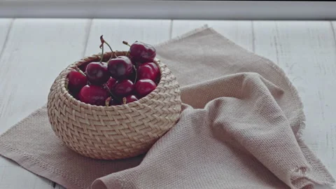 Bright juicy cherry berries fall into a wooden bowl and crumble on the table Stock Footage 156820635