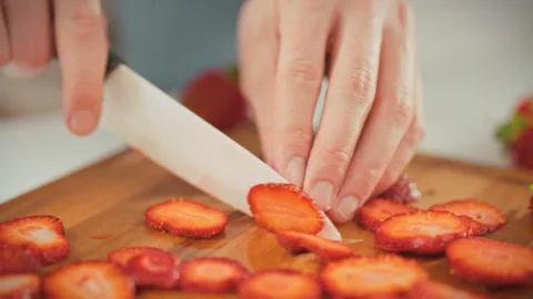 In a bright kitchen a man slices ripe red strawberries into thin slices on a Stock Footage 337937082
