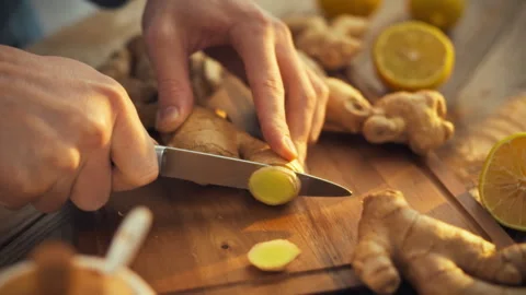 In a bright kitchen a mans hands skillfully chop fresh ginger rhizome releas Stock Footage 331352655