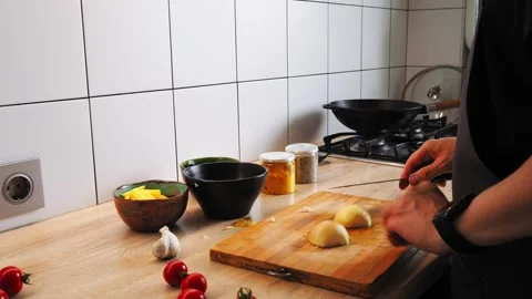 In a bright kitchen, a person skillfully chops fresh ingredients on a wooden 動画素材 316476171