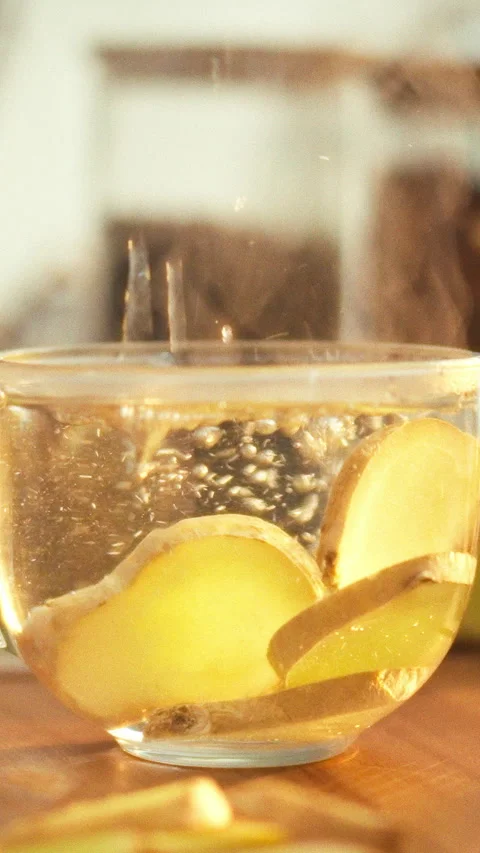 In a bright kitchen a person steeps sliced ginger root in boiling water to c Stock Footage 334397222
