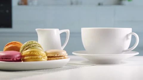 Bright kitchen, on the table there is coffee with a milk jug and a plate with Stock Footage 256496628