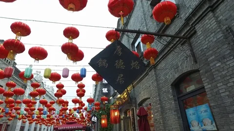 Bright large red Chinese lanterns hang in chains between buildings, Stock-Footage 128933368