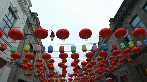 Bright large red Chinese lanterns hang in chains between buildings, decoration Stock Footage 128933929