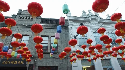Bright large red Chinese lanterns hang in chains between buildings, decoration Stock Footage 128935314