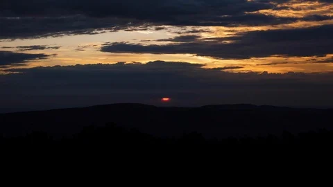 Bright late evening sun disk sets behind black clouds Stock Footage 112436142