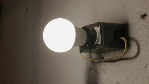 Bright Led Light Bulb Shining on a Gritty Concrete Wall in a Dark Room Video stock 335636720