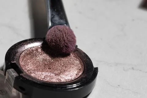 Bright left lighting highlights a worn pink pressed powder compact with a bru Stock Photos