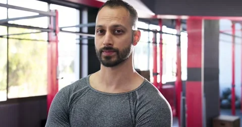 Bright light catching indian man opening eyes, tilting head, smiling in gym Stock Footage 334999434