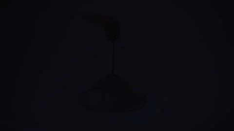 Bright light from lamp hanging on ceiling illuminate dark room Stock Footage 169871089