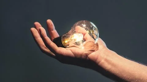 Bright lightbulb held in a hand Stockfoto's