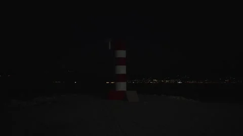 Bright lighthouse guides ships through the night at tranquil shore Stock Footage 296011902