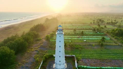 Bright lighthouse rising through misty farm fields Stock Footage 335434127